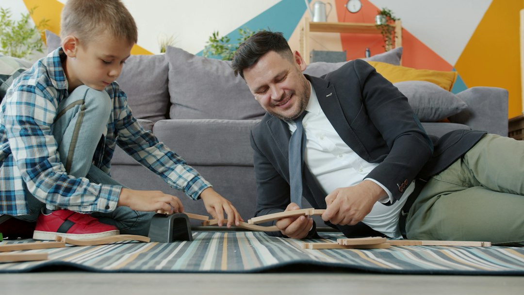 Apa és kisfia a nappali szőnyegén együtt építenek fa vasúti sínt.