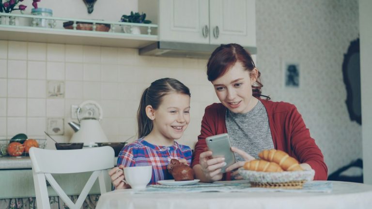 Anya és kamasz lánya együtt nézi a telefont.