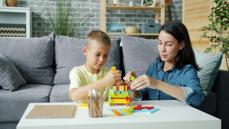 Anya és kisfia közösen épít színes építőelemekből a nappaliban.